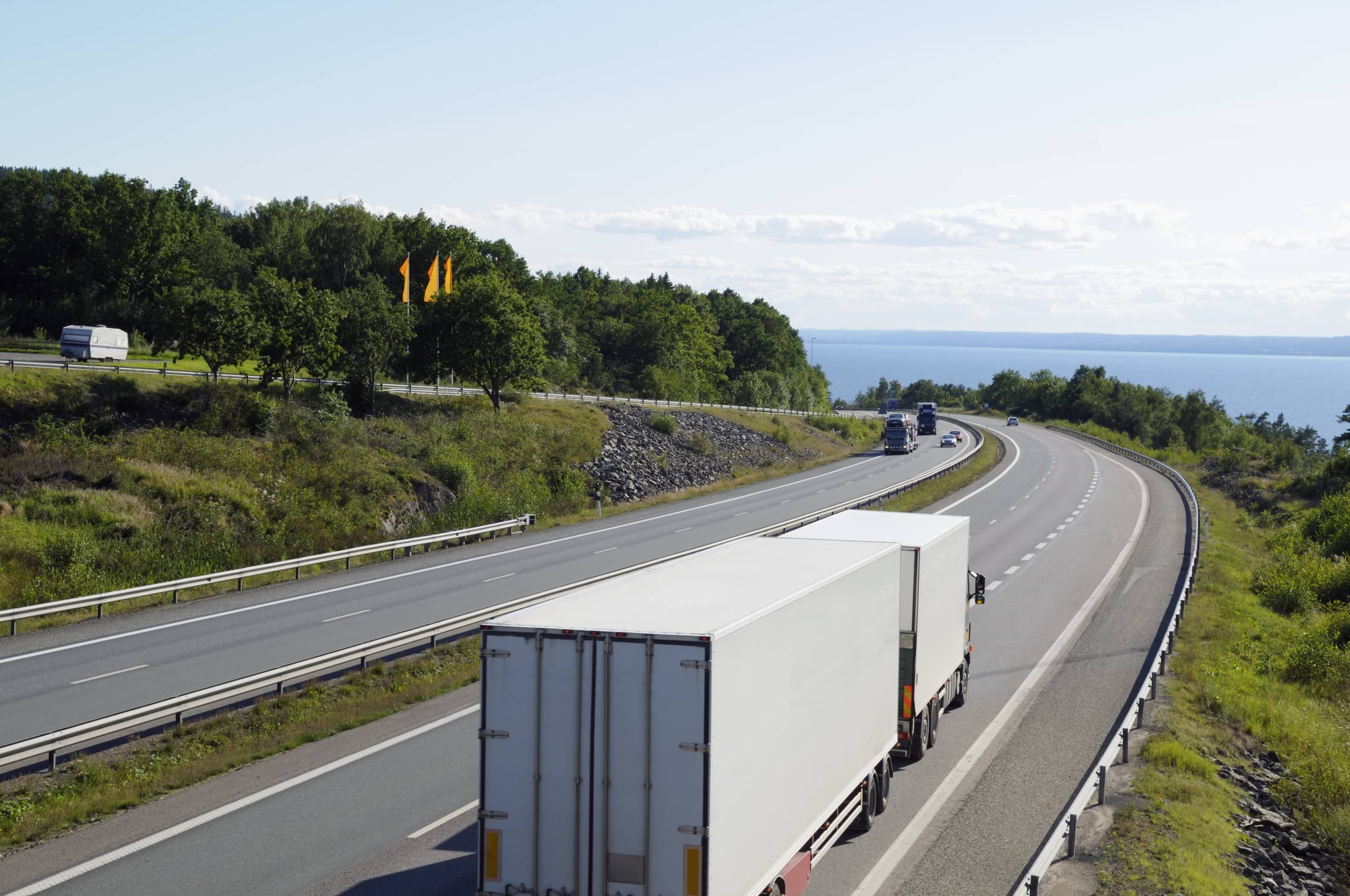 trucking-on-scenic-freeway-sea-in-background-SBI-300980624-scaled-min (1)